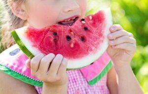 young girl eating a large slice of watermelon