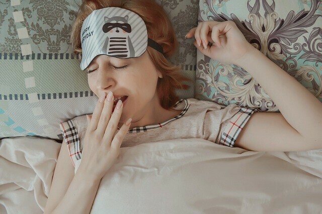 woman yawning in bed struggling to fall asleep