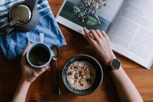 person eating healthy breakfast while reading