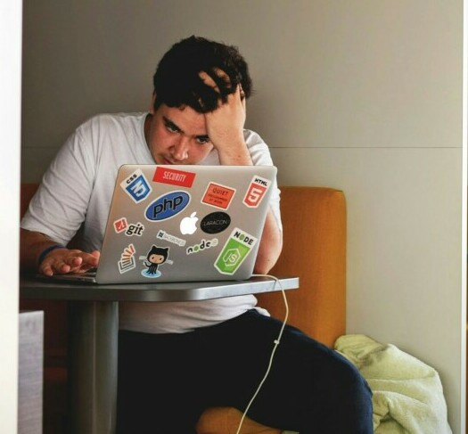 college student who looks stressed looking at laptop